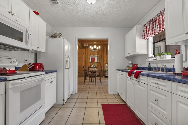 kitchen with a notable chandelier, white cabinetry, light tile patterned floors, white appliances, and dark countertops