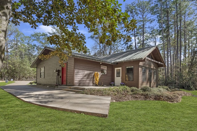 rear view of property with a lawn and metal roof