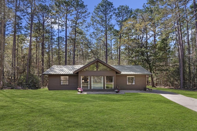 view of front of home featuring a front lawn, metal roof, and driveway