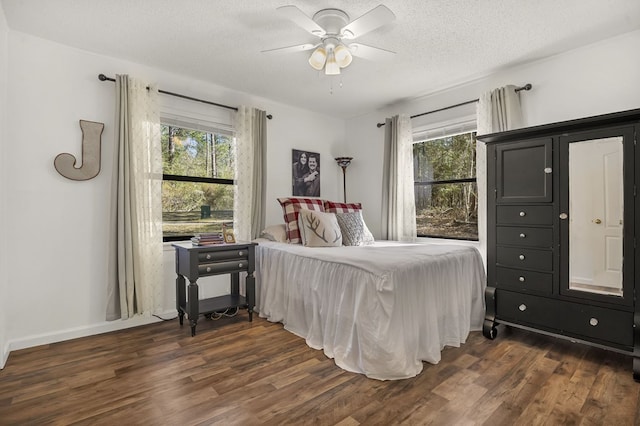 bedroom with dark wood-style floors, multiple windows, a ceiling fan, and a textured ceiling