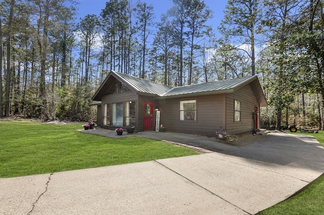 view of front facade featuring a front lawn, driveway, and metal roof