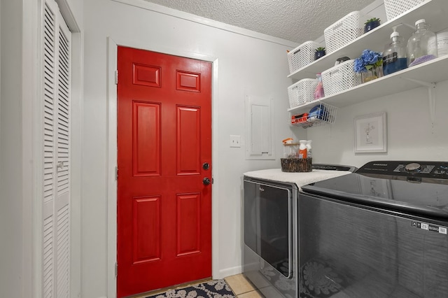 laundry area with light tile patterned flooring, separate washer and dryer, laundry area, and a textured ceiling