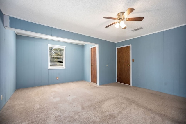 carpeted spare room featuring a textured ceiling, ceiling fan, and crown molding