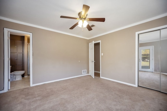 unfurnished bedroom featuring ensuite bathroom, crown molding, ceiling fan, light colored carpet, and a closet