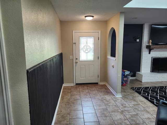 1805 Hanks St, Lufkin, TX 75904 - foyer featuring tile patterned floors, a textured ceiling, a textured wall, and a brick fireplace