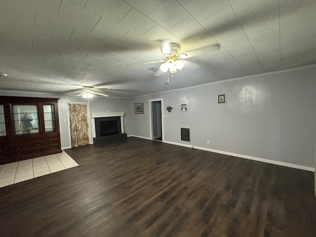 unfurnished living room with crown molding, a fireplace, ceiling fan, and dark wood-type flooring