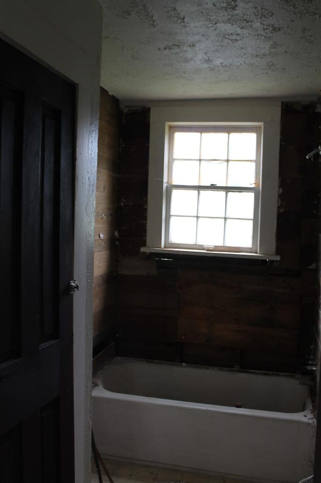 306 S Harrison, San Augustine, TX 75972 - full bath featuring a textured ceiling, a tub, and wooden walls