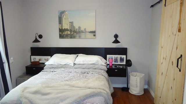 bedroom with a barn door and wood-type flooring