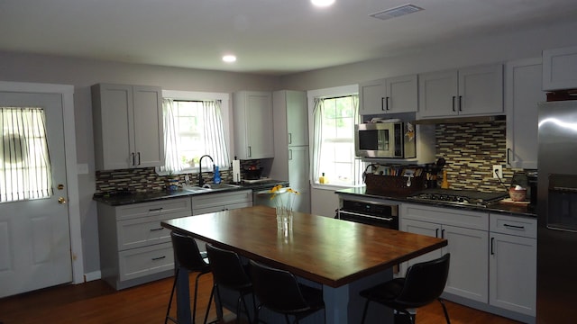 kitchen with sink, stainless steel appliances, dark hardwood / wood-style floors, backsplash, and butcher block countertops