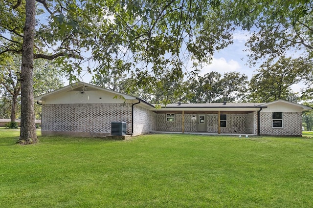 rear view of house with central AC and a yard