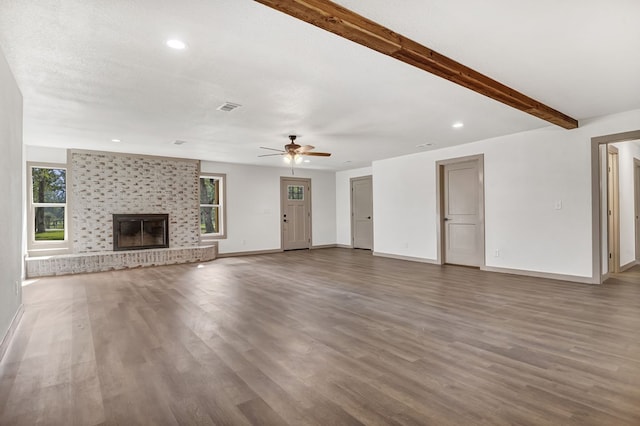 unfurnished living room with a wealth of natural light, ceiling fan, dark hardwood / wood-style floors, and a brick fireplace