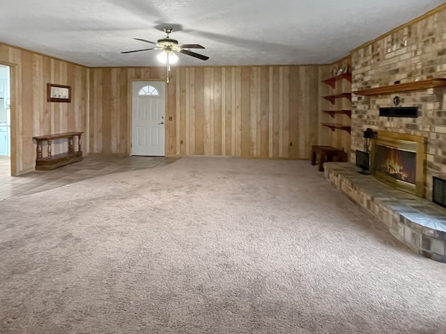 33963 US Highway 96, Buna, TX 77612 - unfurnished living room featuring carpet, a textured ceiling, a ceiling fan, a brick fireplace, and wooden walls