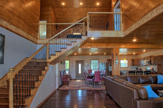 unfurnished living room with a towering ceiling, wooden ceiling, and dark hardwood / wood-style floors