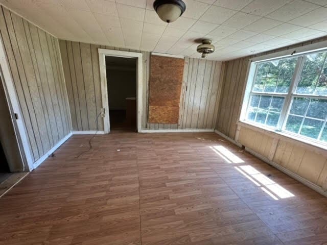 spare room featuring hardwood / wood-style flooring and wood walls