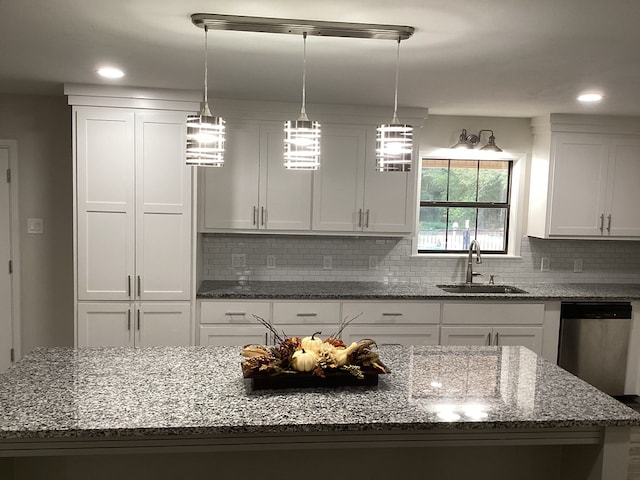 kitchen with sink, white cabinets, stone countertops, decorative light fixtures, and stainless steel dishwasher