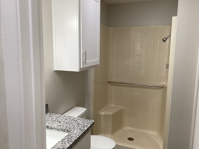 bathroom with walk in shower, vanity, and toilet