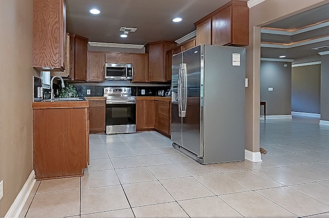 kitchen with sink, decorative backsplash, ornamental molding, appliances with stainless steel finishes, and light tile patterned flooring