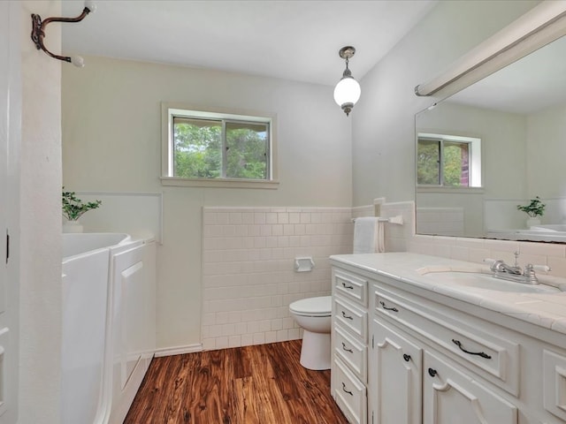 200 Platt Rd, Lufkin, TX 75904 - bathroom featuring tile walls, toilet, healthy amount of natural light, a garden tub, and wood finished floors