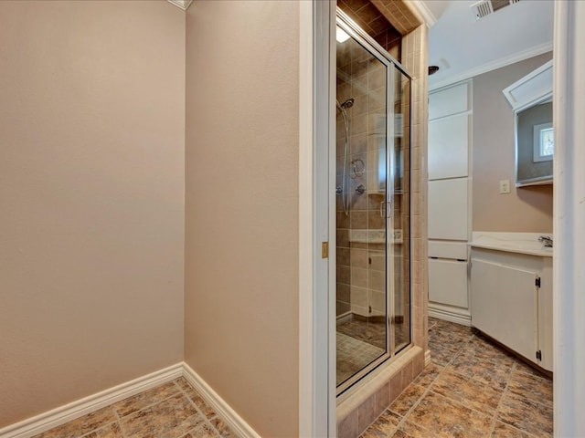 bathroom with ornamental molding, vanity, baseboards, visible vents, and a stall shower
