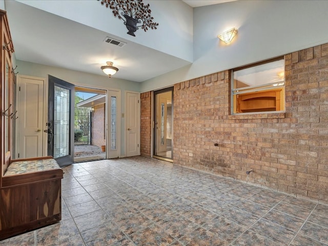 entryway with visible vents and brick wall