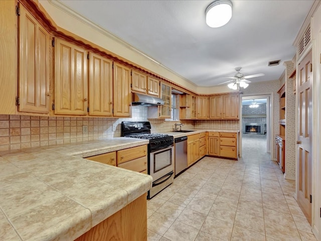 kitchen featuring tasteful backsplash, stainless steel appliances, a large fireplace, under cabinet range hood, and ceiling fan