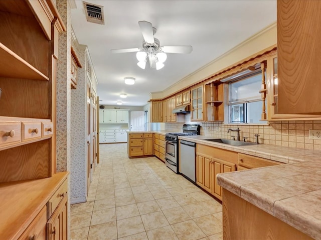 kitchen with tasteful backsplash, stainless steel appliances, under cabinet range hood, a sink, and visible vents