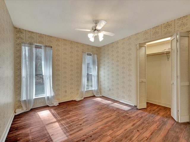 unfurnished bedroom with baseboards, wood finished floors, ceiling fan, and a closet