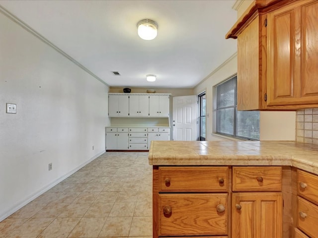 kitchen featuring brown cabinetry, crown molding, visible vents, a peninsula, and light countertops