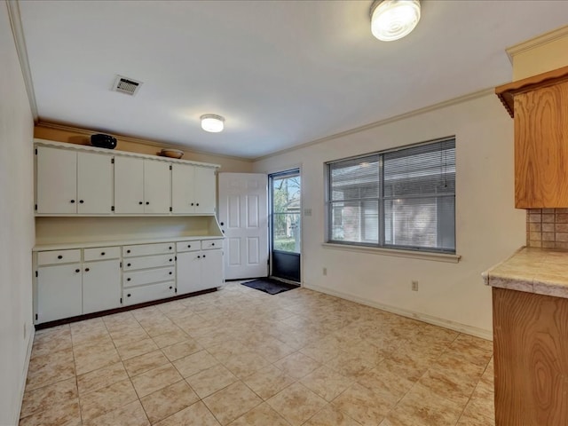 kitchen with baseboards, light countertops, ornamental molding, white cabinetry, and visible vents
