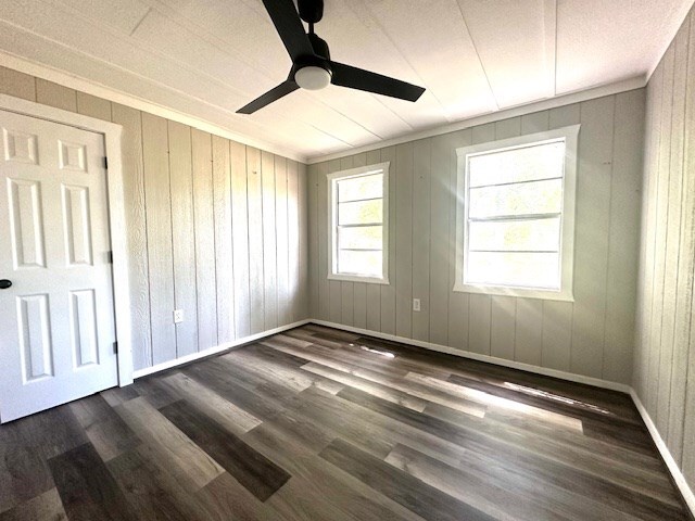 308 Pine, Diboll, TX 75941 - unfurnished bedroom featuring ceiling fan, wood walls, and dark wood-style floors