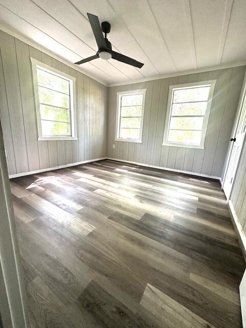 308 Pine, Diboll, TX 75941 - spare room featuring baseboards, wooden walls, ceiling fan, and wood finished floors
