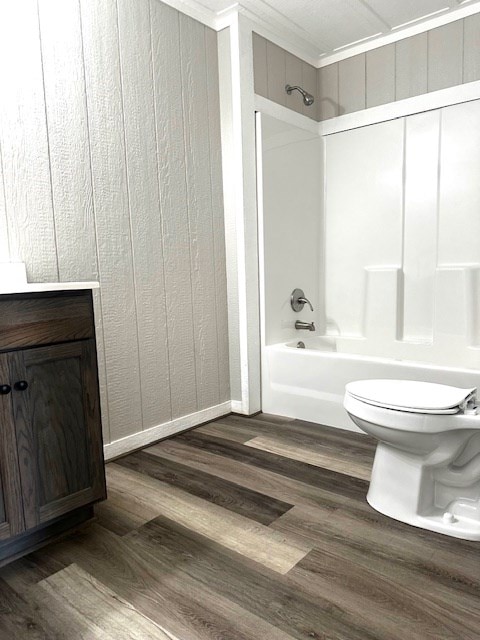 bathroom featuring toilet, baseboards, shower / washtub combination, and wood finished floors