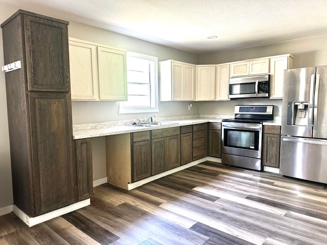 308 Pine, Diboll, TX 75941 - kitchen featuring dark wood-style flooring, a sink, light countertops, baseboards, and stainless steel appliances