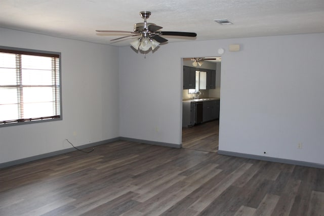 empty room with a textured ceiling, dark hardwood / wood-style floors, ceiling fan, and sink