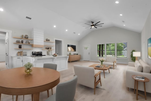 living room featuring ceiling fan, light hardwood / wood-style flooring, and vaulted ceiling