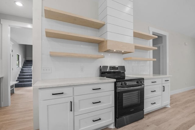 kitchen with tasteful backsplash, gas range, white cabinetry, and light hardwood / wood-style floors