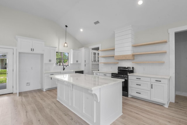 kitchen with white cabinets, stainless steel stove, light wood-type flooring, decorative light fixtures, and a kitchen island