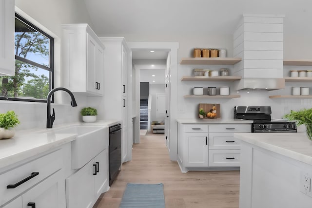 kitchen with light stone counters, sink, white cabinets, and black appliances