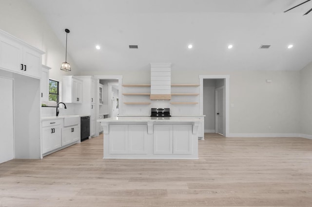 kitchen with a center island, hanging light fixtures, light hardwood / wood-style flooring, stainless steel range oven, and white cabinetry