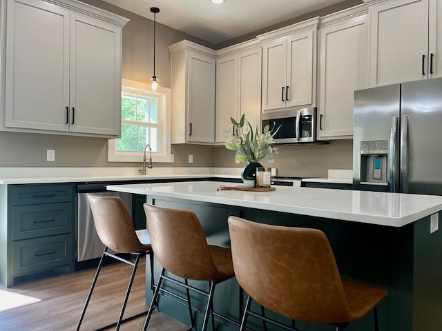 105 Cooper Rd, Zavalla, TX 75980 - kitchen featuring appliances with stainless steel finishes, light countertops, a kitchen island, light wood-style floors, and decorative light fixtures