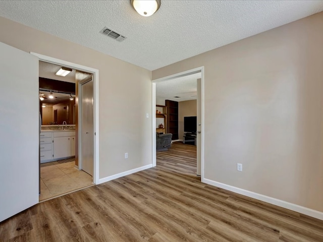 spare room featuring a textured ceiling, light wood-type flooring, and sink