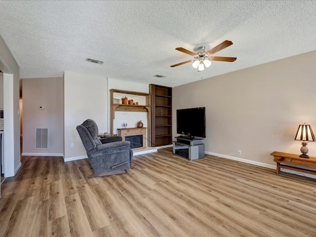 interior space featuring ceiling fan, light wood-type flooring, and a textured ceiling