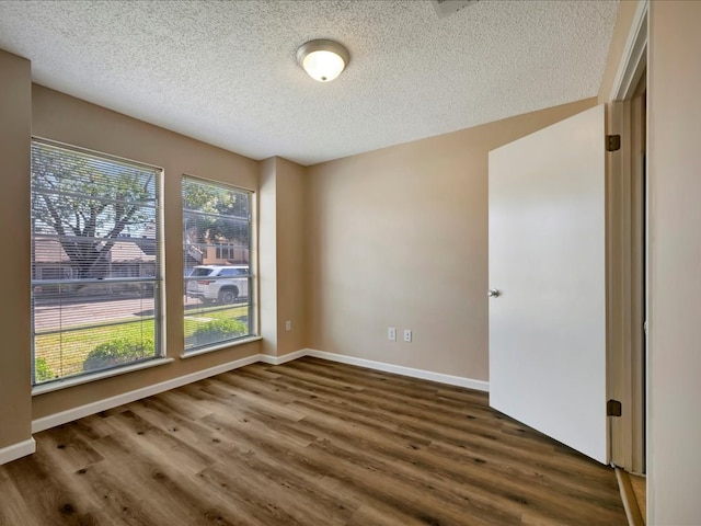 empty room featuring a textured ceiling and dark hardwood / wood-style floors