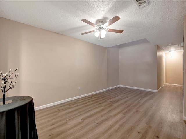 empty room featuring ceiling fan, light hardwood / wood-style floors, and a textured ceiling