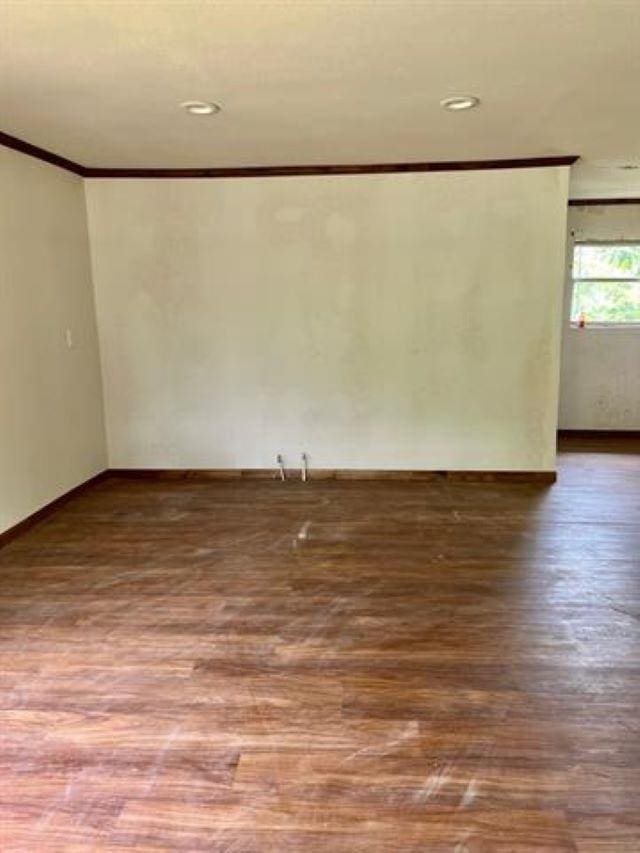 empty room with wood-type flooring and crown molding