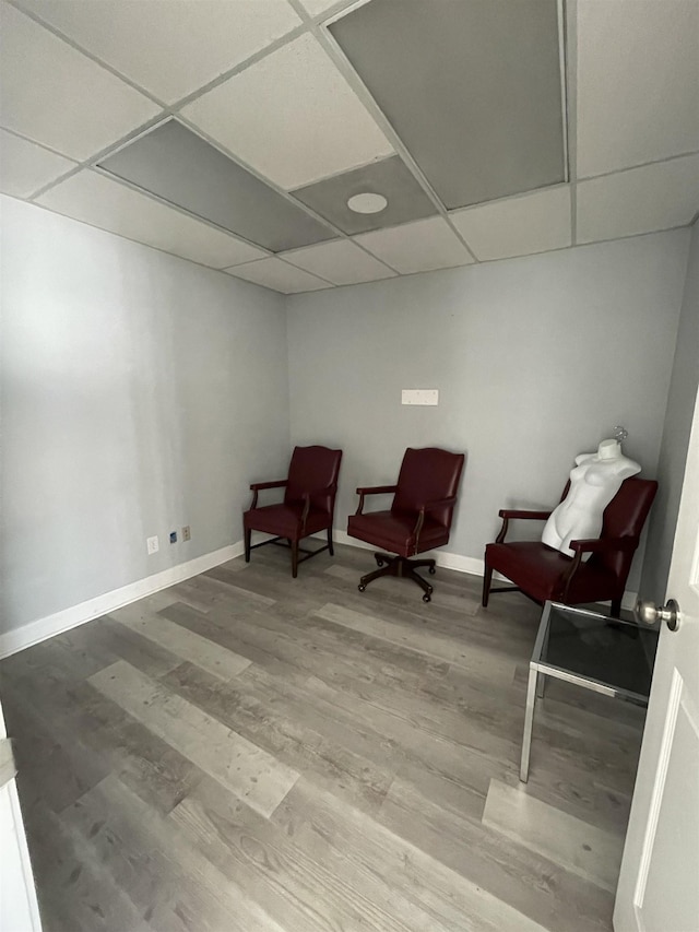 sitting room with hardwood / wood-style flooring and a drop ceiling