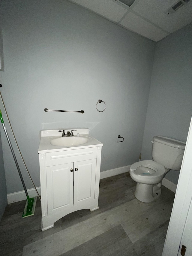 bathroom with toilet, a drop ceiling, vanity, and hardwood / wood-style flooring