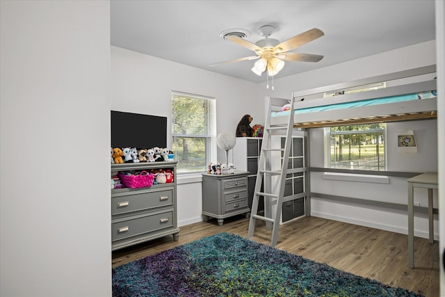 bedroom with multiple windows, ceiling fan, and dark hardwood / wood-style flooring