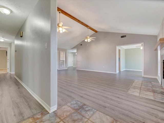 unfurnished living room with lofted ceiling with beams, ceiling fan, a fireplace, and visible vents