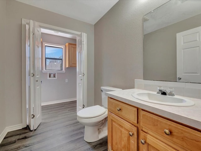 bathroom featuring baseboards, vanity, toilet, and wood finished floors